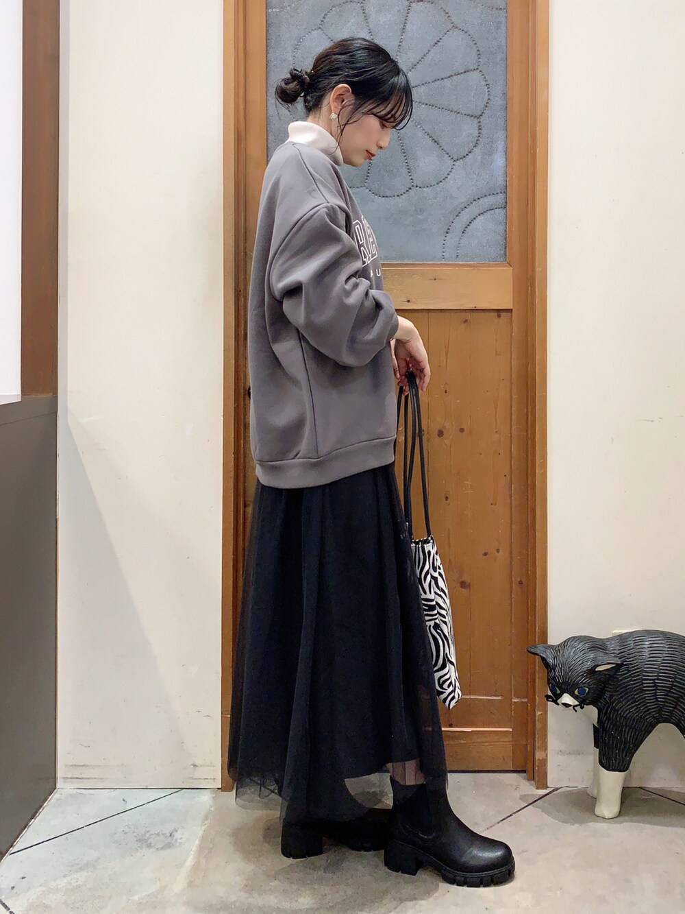 ホワイト系のニット/セーター、グレー系のスウェット、ブラック系のスカートを着用したレディースの冬コーディネートの2枚目の写真