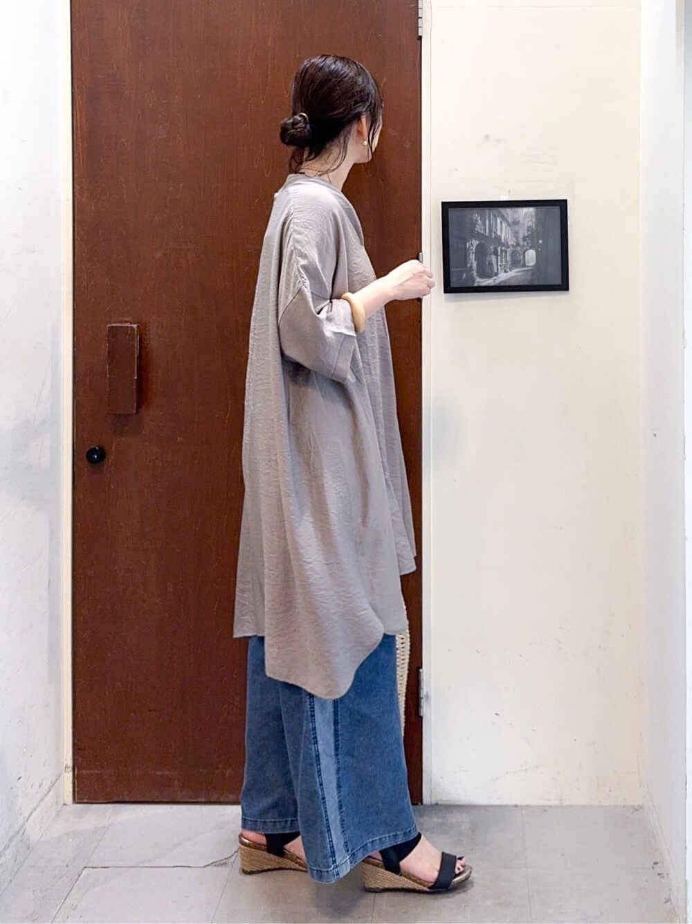 ブラウン系のチュニック、ブルー系のデニムパンツ、ブラック系のサンダルを着用したレディースの夏コーディネートの4枚目の写真
