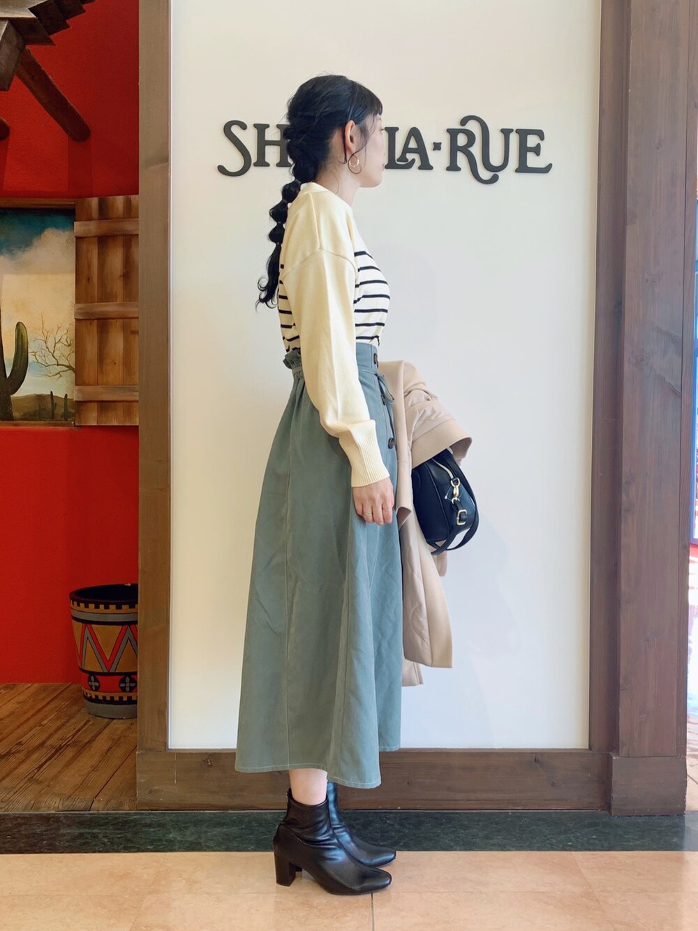 ホワイト系のニット/セーター、ベージュ系のその他アウター、グリーン系のスカートを着用したレディースの冬コーディネートの3枚目の写真