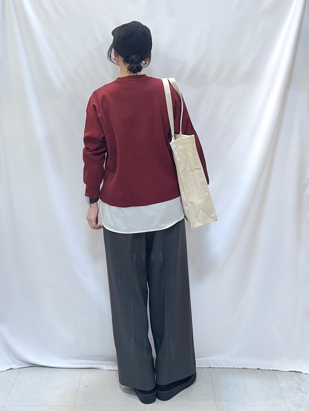 レッド系のニット/セーター、グレー系のその他パンツ、ブラック系のブーツを着用したレディースの秋コーディネートの3枚目の写真