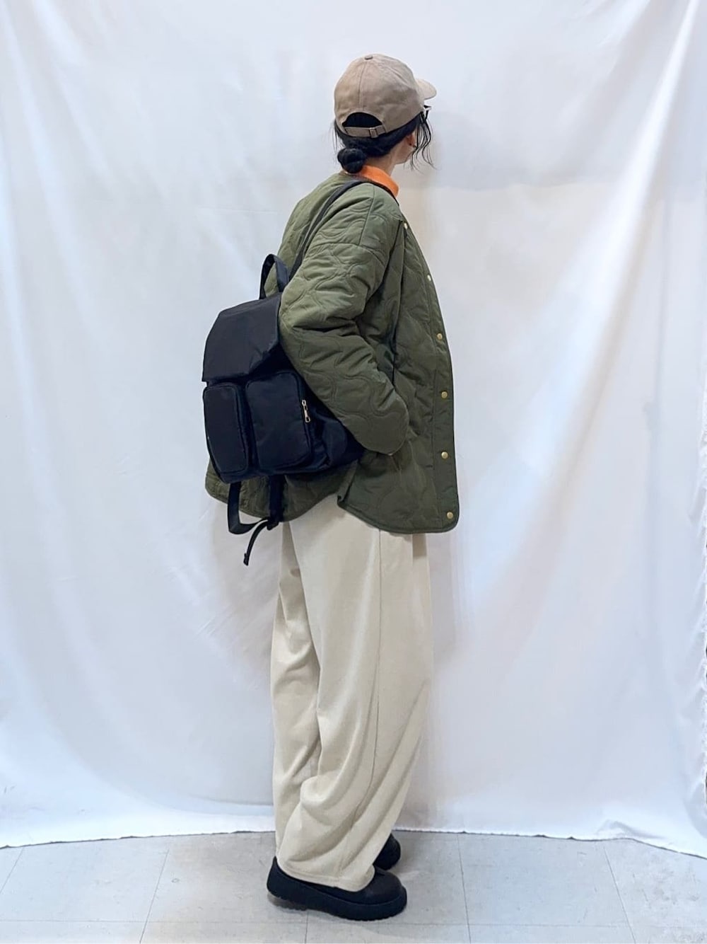 グリーン系のブルゾン、ブラウン系のニット/セーター、オレンジ系のTシャツ/カットソーを着用したレディースの秋コーディネートの4枚目の写真