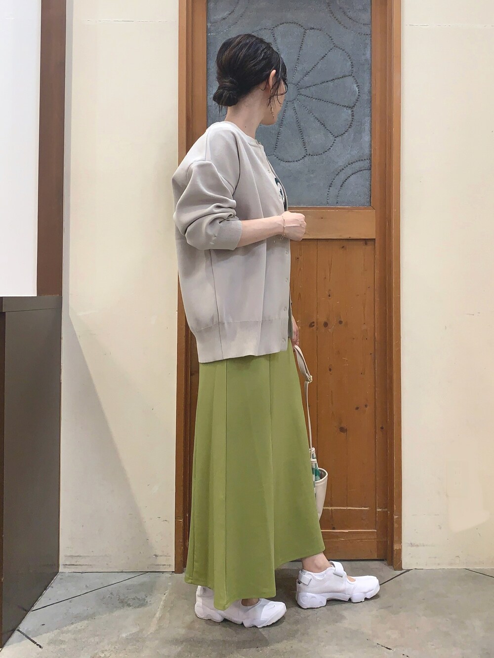 ホワイト系のTシャツ/カットソー、ベージュ系のカーディガン/ボレロ、グリーン系のスカートを着用したレディースの秋コーディネートの2枚目の写真