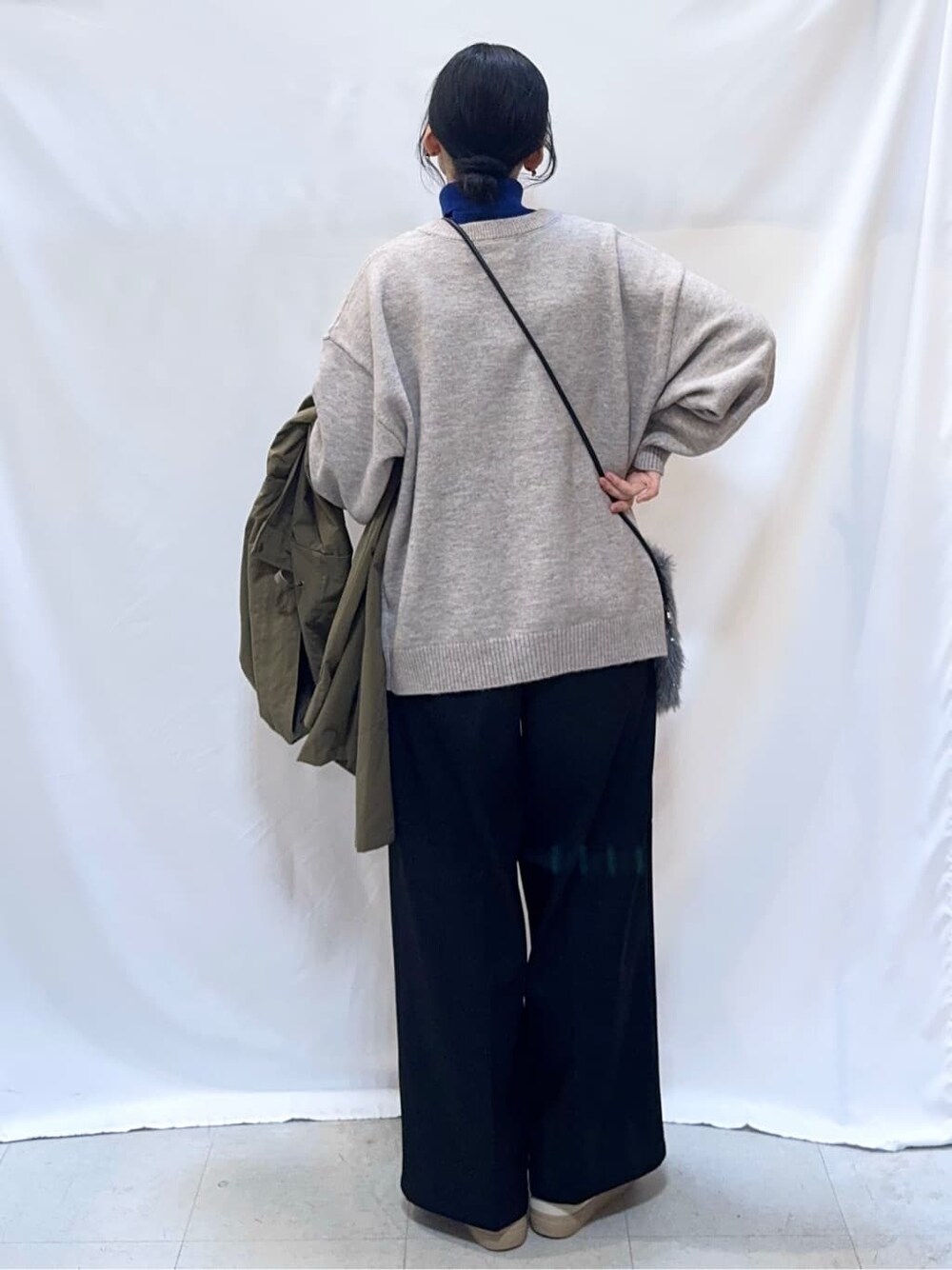 グリーン系のミリタリージャケット、グレー系のニット/セーター、ブルー系のニット/セーターを着用したレディースの冬コーディネートの7枚目の写真