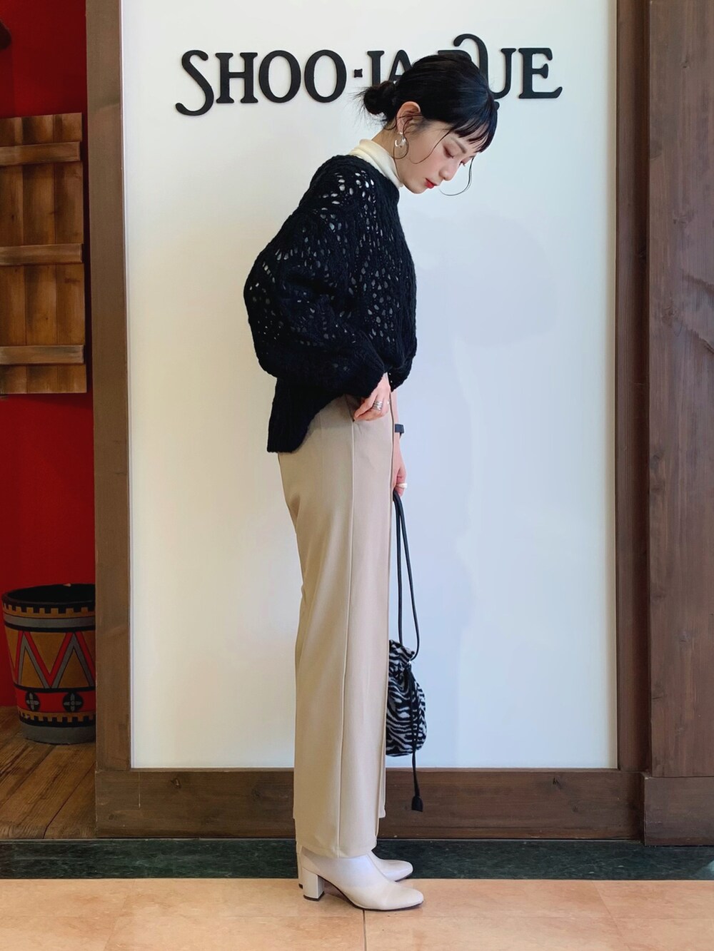 ブラック系のニット/セーター、ホワイト系のTシャツ/カットソー、ベージュ系のその他パンツを着用したレディースの冬コーディネートの2枚目の写真