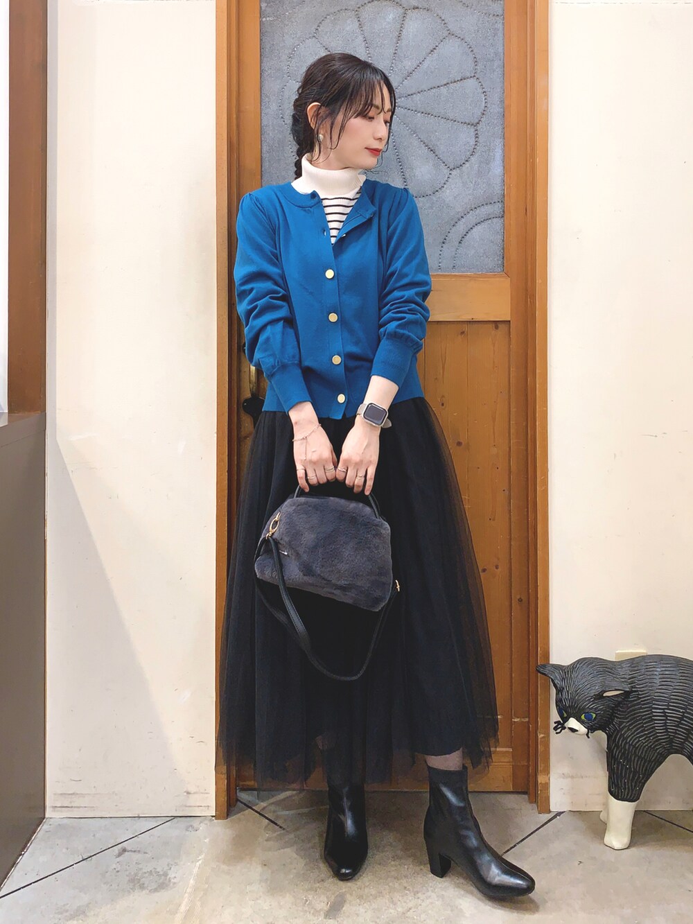 ホワイト系のニット/セーター、ブルー系のカーディガン/ボレロ、ブラック系のスカートを着用したレディースの冬コーディネートの2枚目の写真