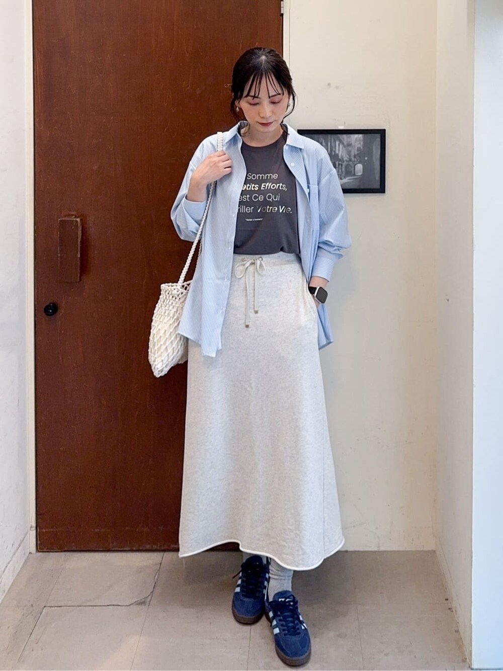 ブルー系のシャツ/ブラウス、グレー系のスカート、ホワイト系のショルダーバッグを着用したレディースの春コーディネートの2枚目の写真