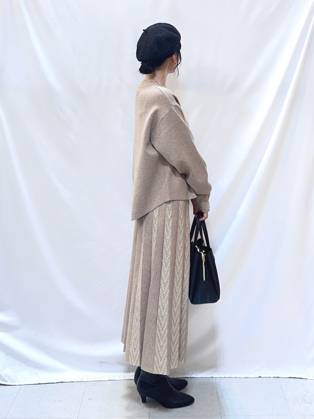 ベージュ系のニット/セーター、ベージュ系のスカート、ブラック系のトートバッグを着用したレディースの冬コーディネートの4枚目の写真