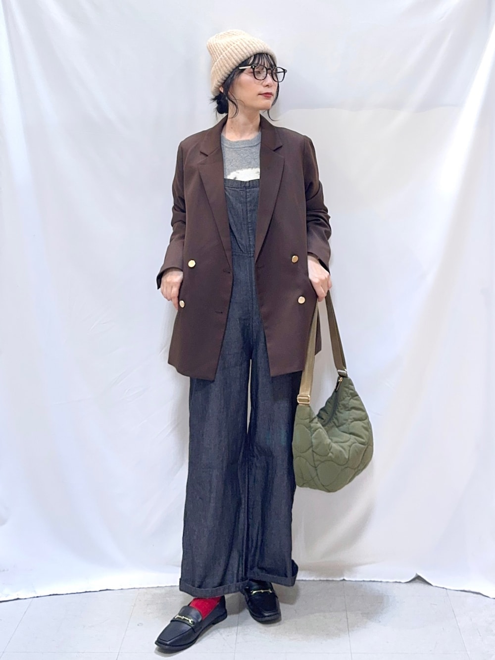 ブラウン系のテーラードジャケット、グレー系のニット/セーター、ブラック系のサロペット/オーバーオールを着用したレディースの秋コーディネートの2枚目の写真