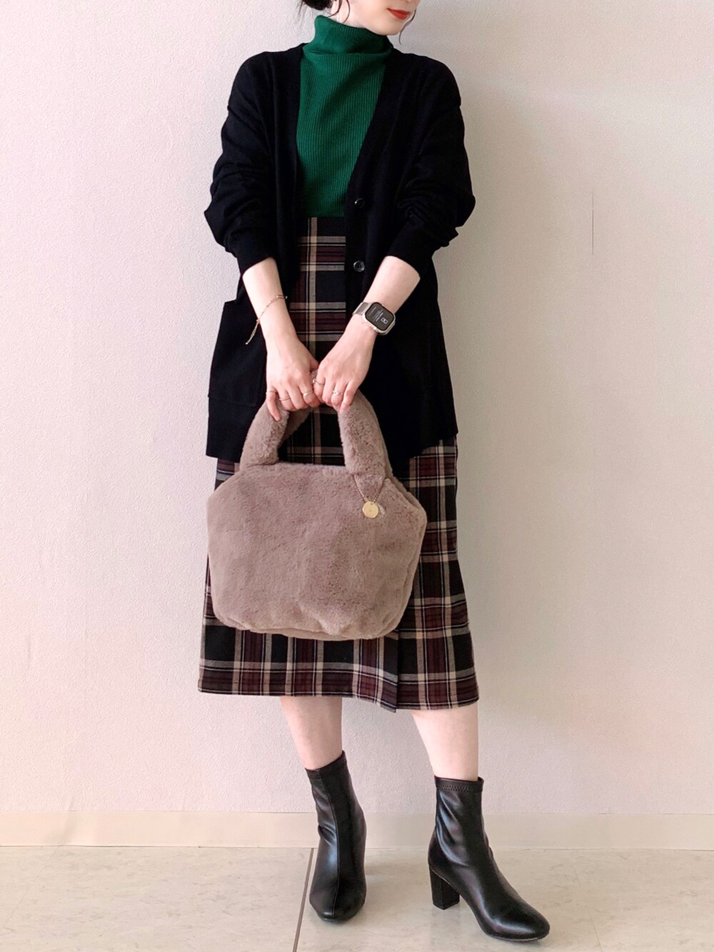 グリーン系のニット/セーター、ブラック系のカーディガン/ボレロ、ブラック系のスカートを着用したレディースの秋コーディネートの4枚目の写真