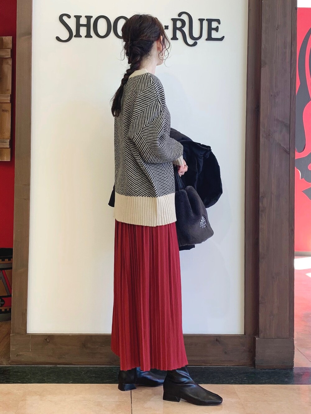 ベージュ系のニット/セーター、ブラック系のダウンジャケット/コート、レッド系のその他パンツを着用したレディースの秋コーディネートの3枚目の写真