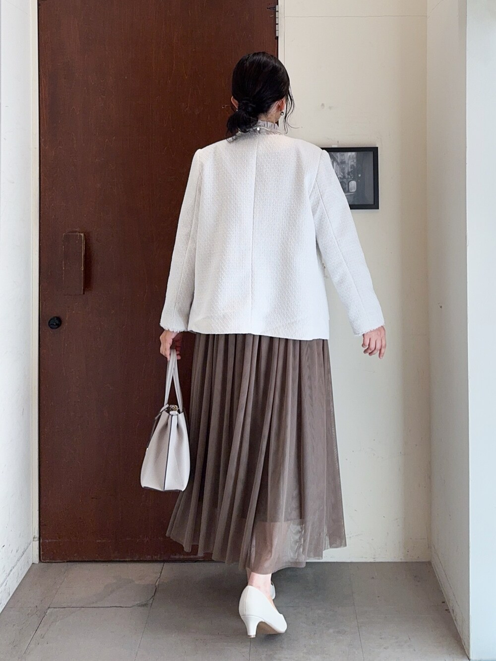 ベージュ系のノーカラージャケット、ベージュ系のシャツ/ブラウス、ブラウン系のスカートを着用したレディースの冬コーディネートの4枚目の写真