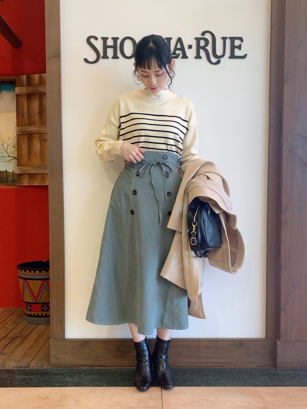 ホワイト系のニット/セーター、ベージュ系のその他アウター、グリーン系のスカートを着用したレディースの冬コーディネートの2枚目の写真