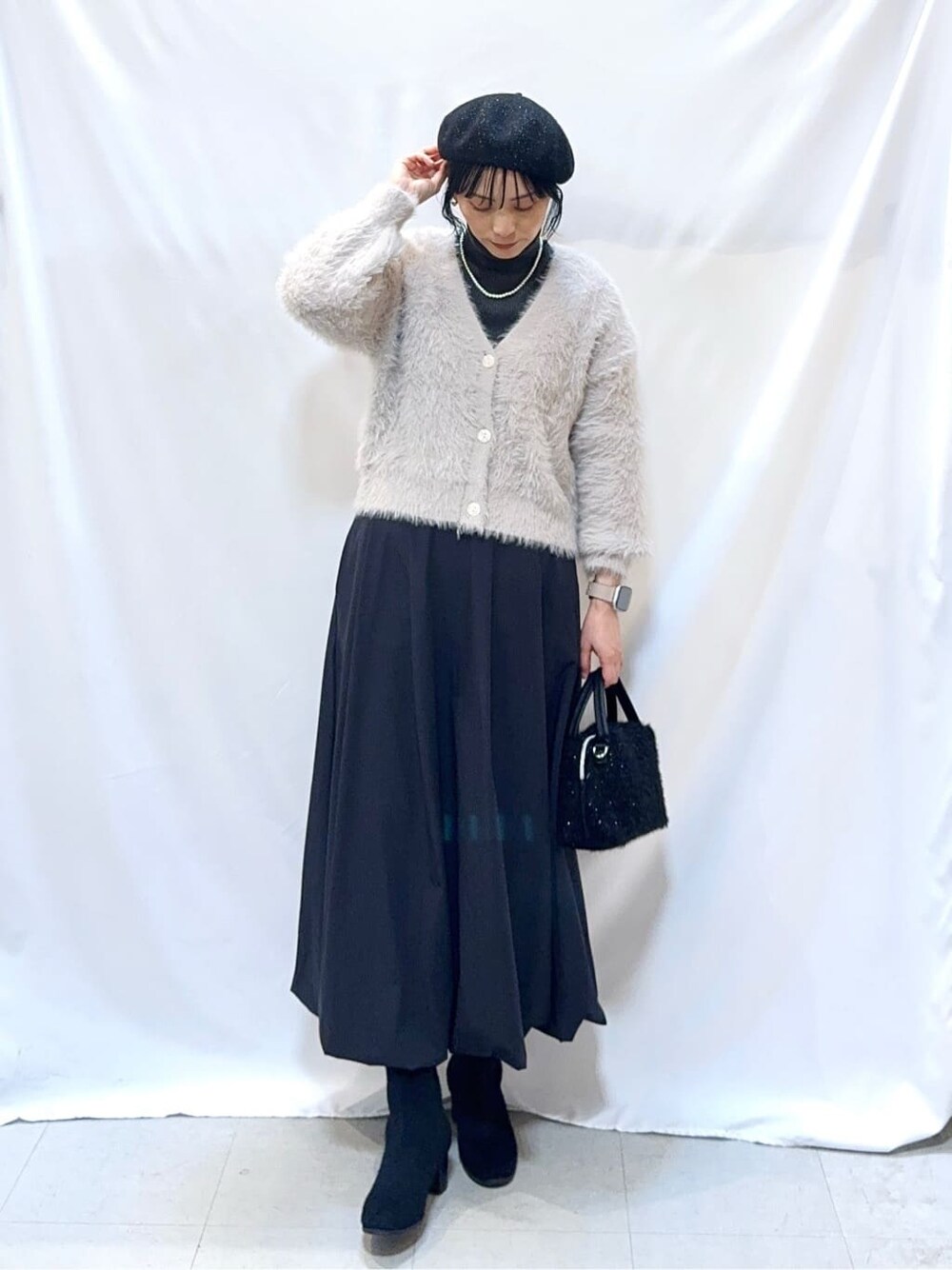 グレー系のカーディガン/ボレロ、グレー系のニット/セーター、ブラック系のスカートを着用したレディースの冬コーディネートの2枚目の写真