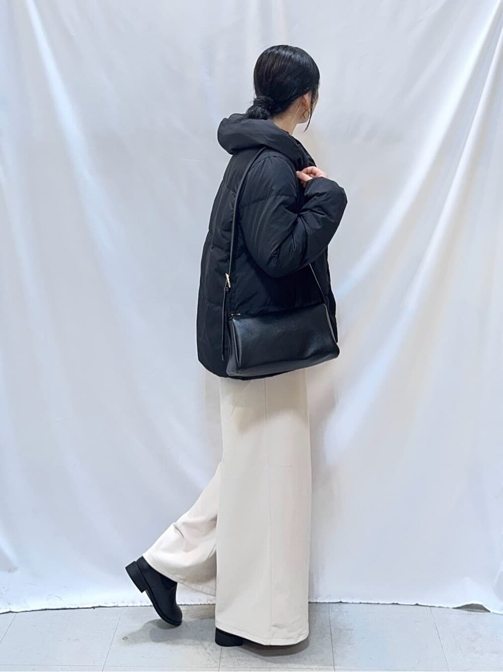 ブラック系のダウンジャケット/コート、ピンク系のニット/セーター、ホワイト系のその他パンツを着用したレディースの冬コーディネートの2枚目の写真