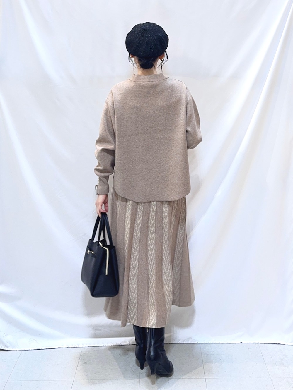 ベージュ系のニット/セーター、ベージュ系のスカート、ブラック系のトートバッグを着用したレディースの冬コーディネートの5枚目の写真