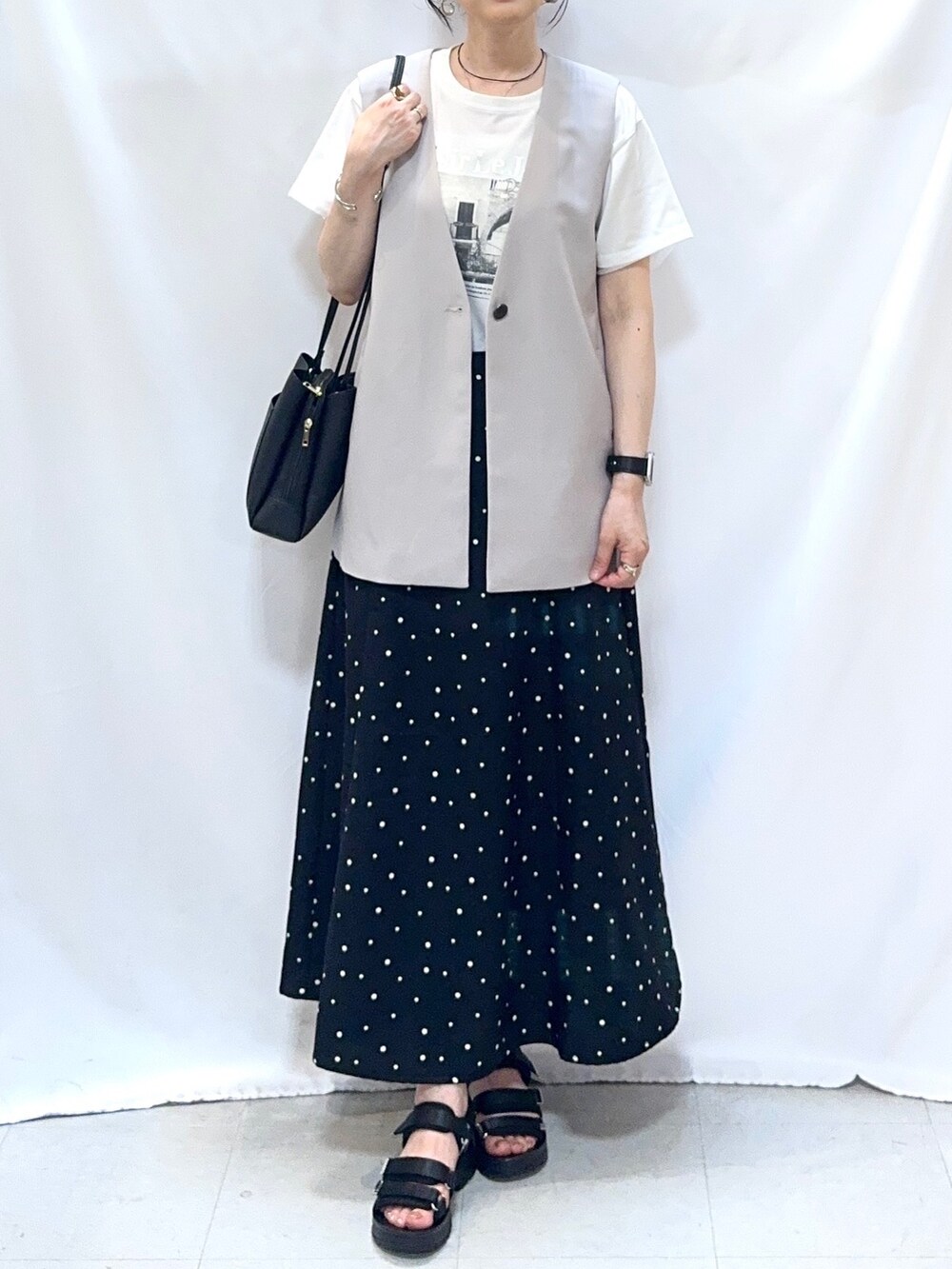 ベージュ系のベスト、ホワイト系のTシャツ/カットソー、ブラック系のスカートを着用したレディースの夏コーディネートの6枚目の写真