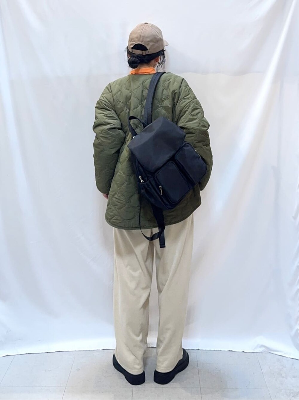 グリーン系のブルゾン、ブラウン系のニット/セーター、オレンジ系のTシャツ/カットソーを着用したレディースの秋コーディネートの5枚目の写真