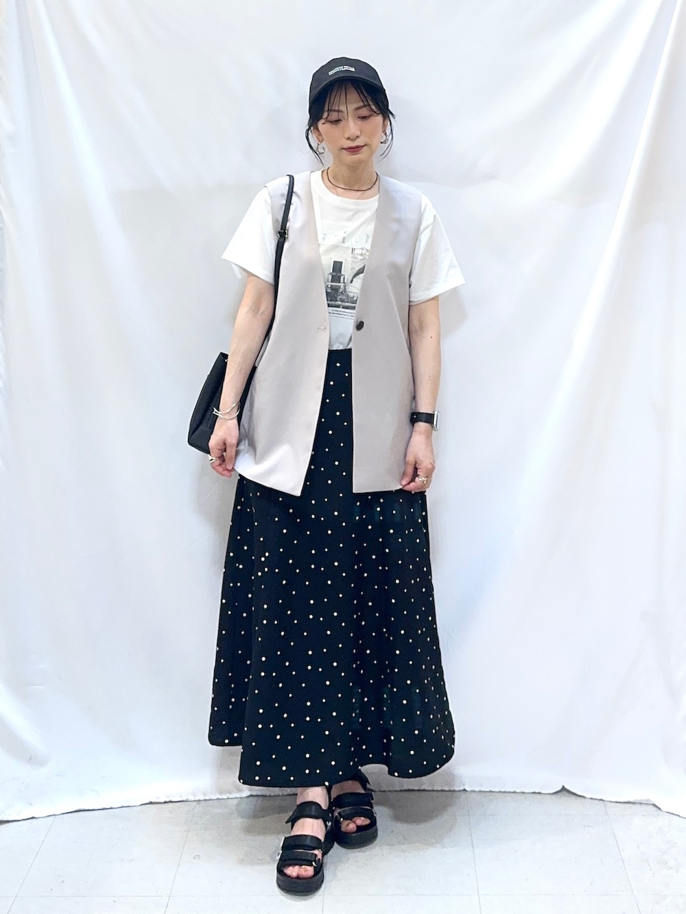 ベージュ系のベスト、ホワイト系のTシャツ/カットソー、ブラック系のスカートを着用したレディースの夏コーディネートの2枚目の写真