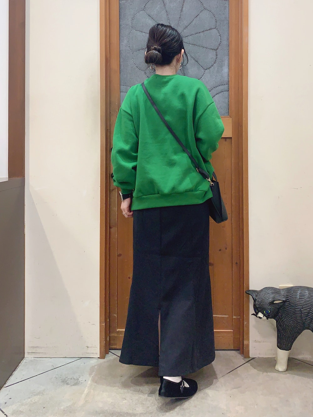 グリーン系のスウェット、ブラック系のスカート、ブラック系のショルダーバッグを着用したレディースの冬コーディネートの3枚目の写真