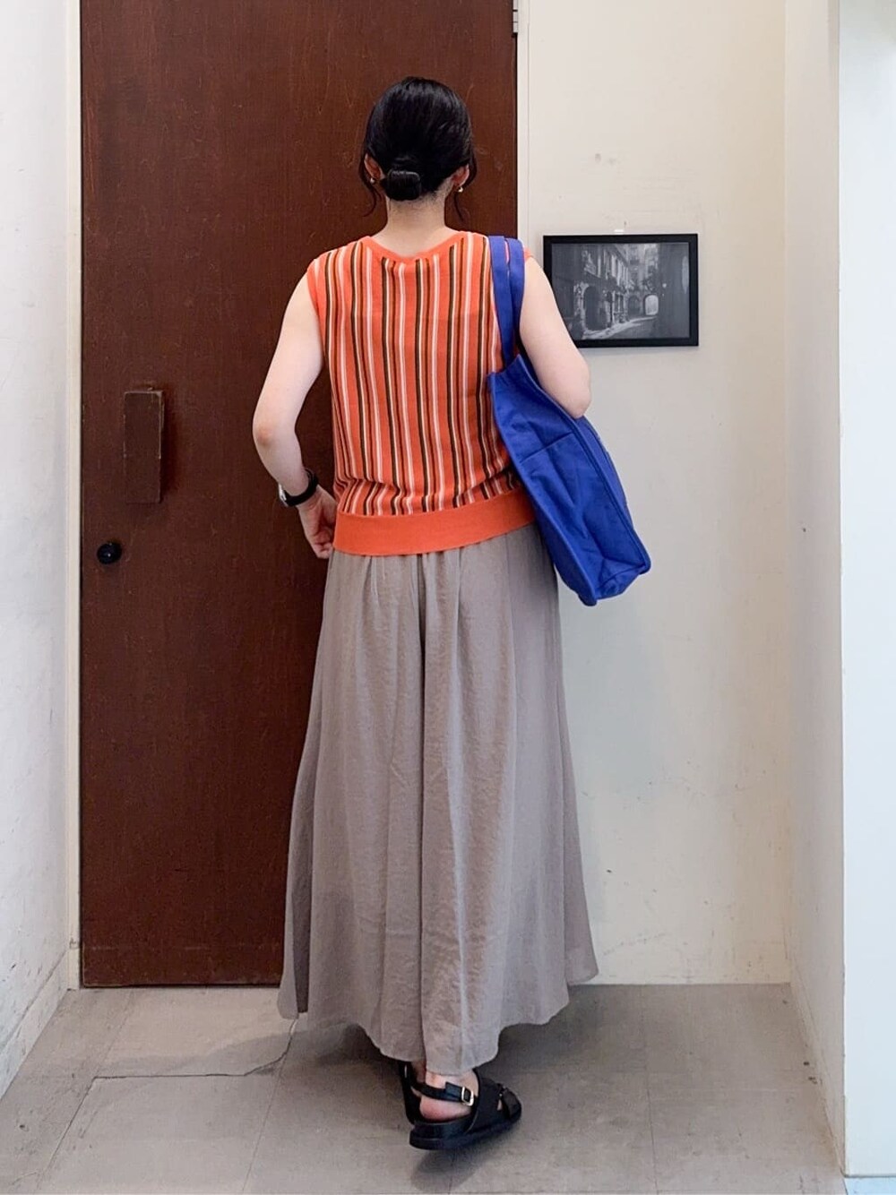 オレンジ系のニット/セーター、ブラウン系のその他パンツ、ブルー系のトートバッグを着用したレディースの夏コーディネートの4枚目の写真