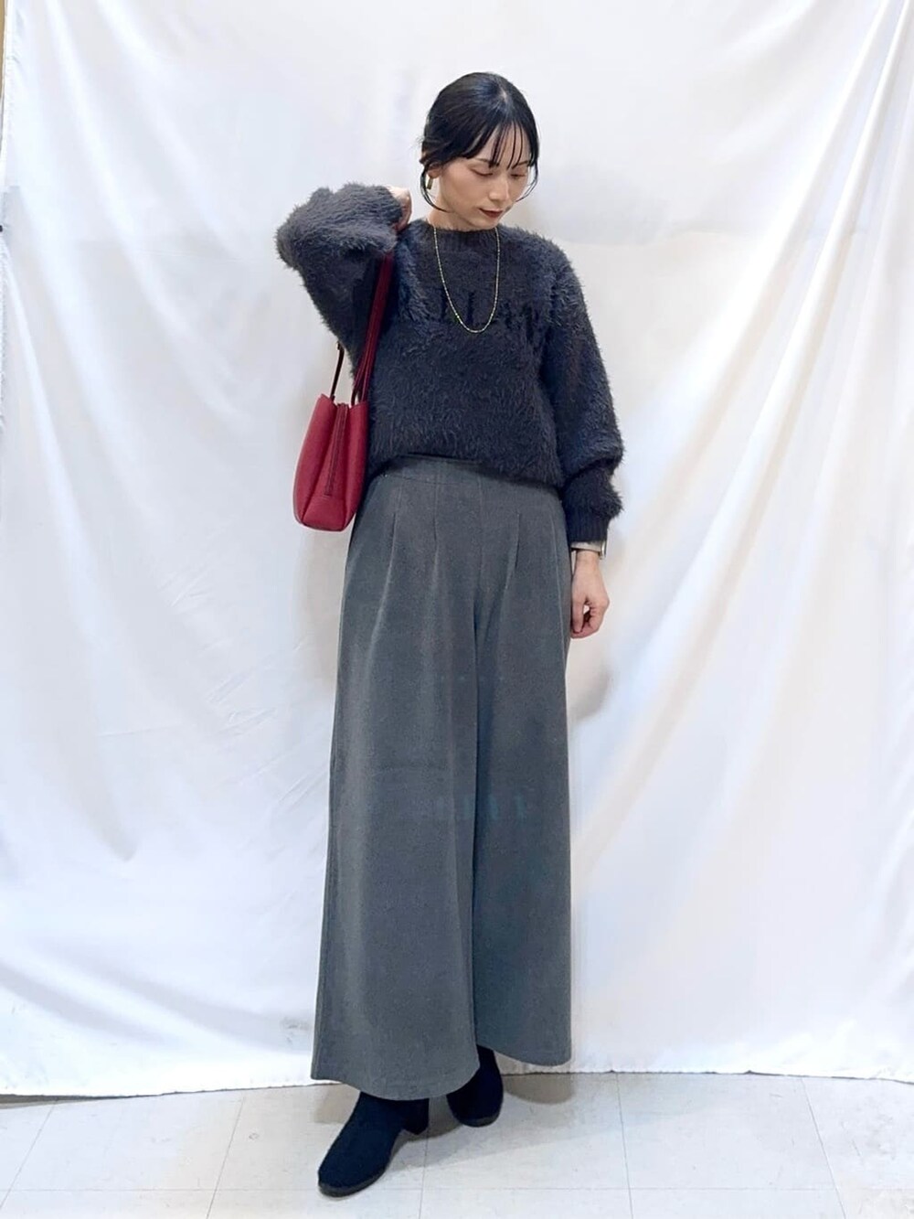 グレー系のニット/セーター、グレー系のその他パンツ、ブラック系のブーツを着用したレディースの冬コーディネートの2枚目の写真