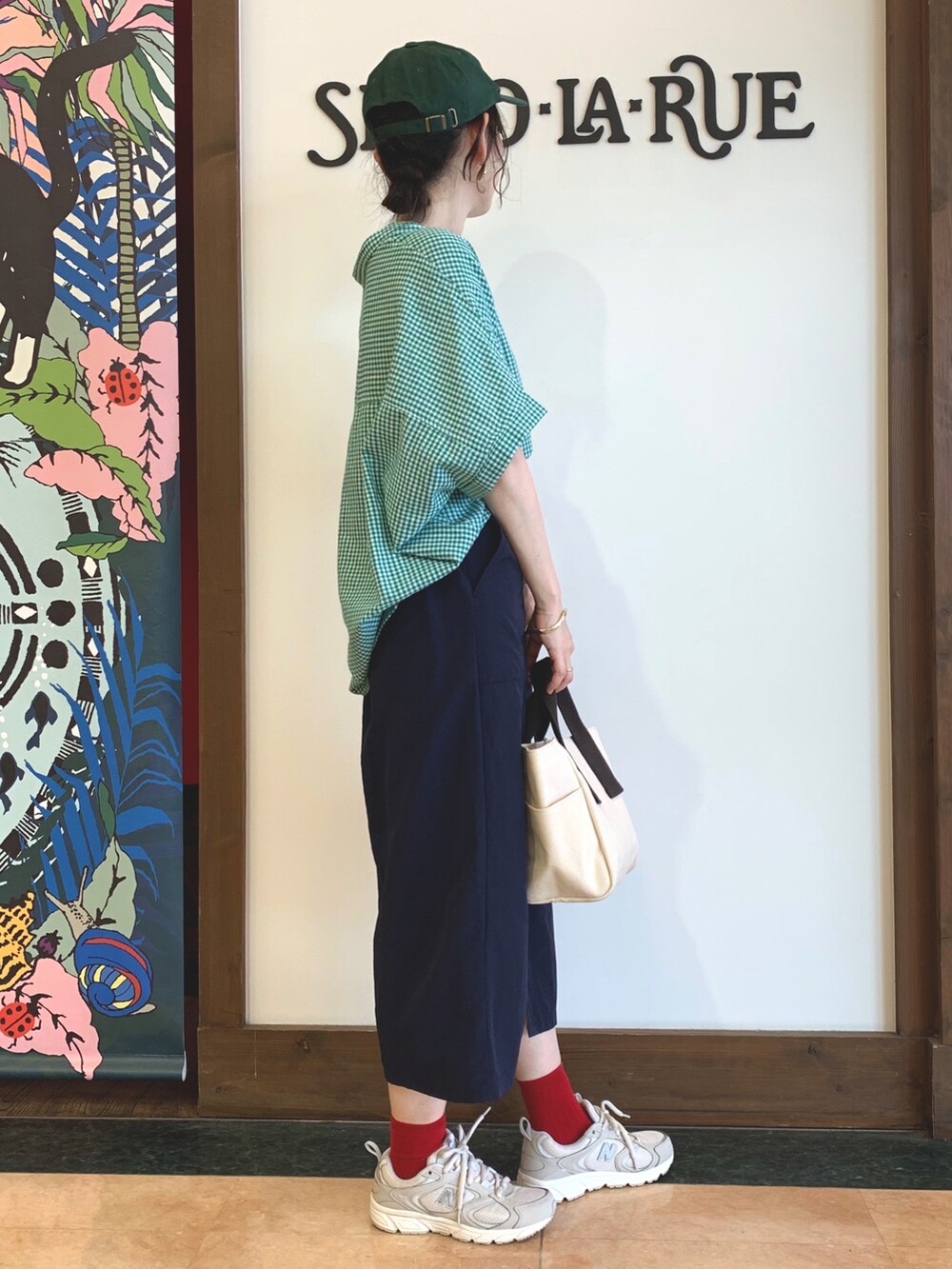 グリーン系のシャツ/ブラウス、ブルー系のスカート、ベージュ系のトートバッグを着用したレディースの春コーディネートの2枚目の写真