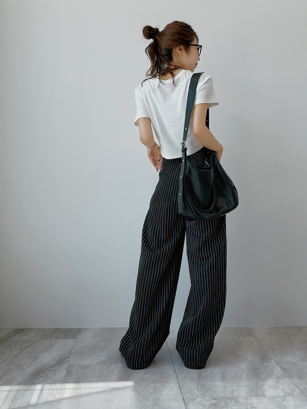 ホワイト系のTシャツ/カットソー、ブラック系のスラックス、ブラック系のサンダルを着用したレディースの春コーディネートの2枚目の写真