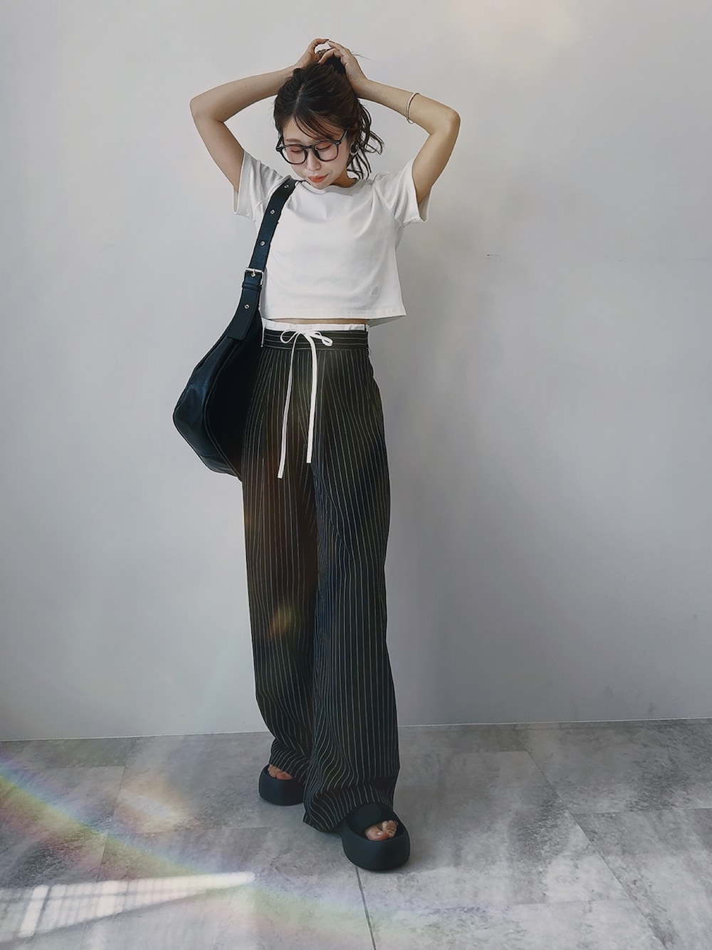 ホワイト系のTシャツ/カットソー、ブラック系のスラックス、ブラック系のサンダルを着用したレディースの春コーディネートの3枚目の写真