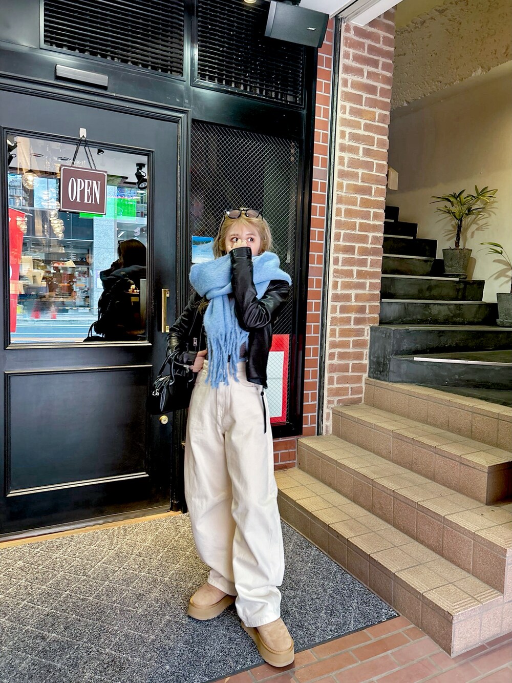 グレー系のブーツ、ホワイト系のデニムパンツ、ブラック系のライダースジャケットを着用したレディースの春コーディネートの3枚目の写真