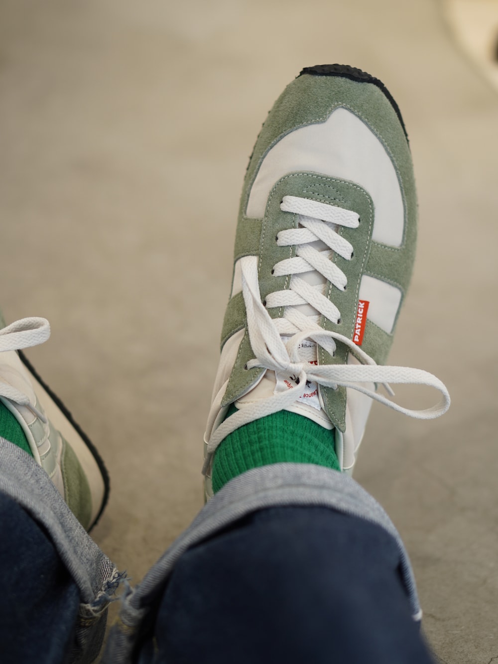 グリーン系のトートバッグ、ブルー系のデニムパンツ、グリーン系のスニーカーを着用したメンズの夏コーディネートの2枚目の写真