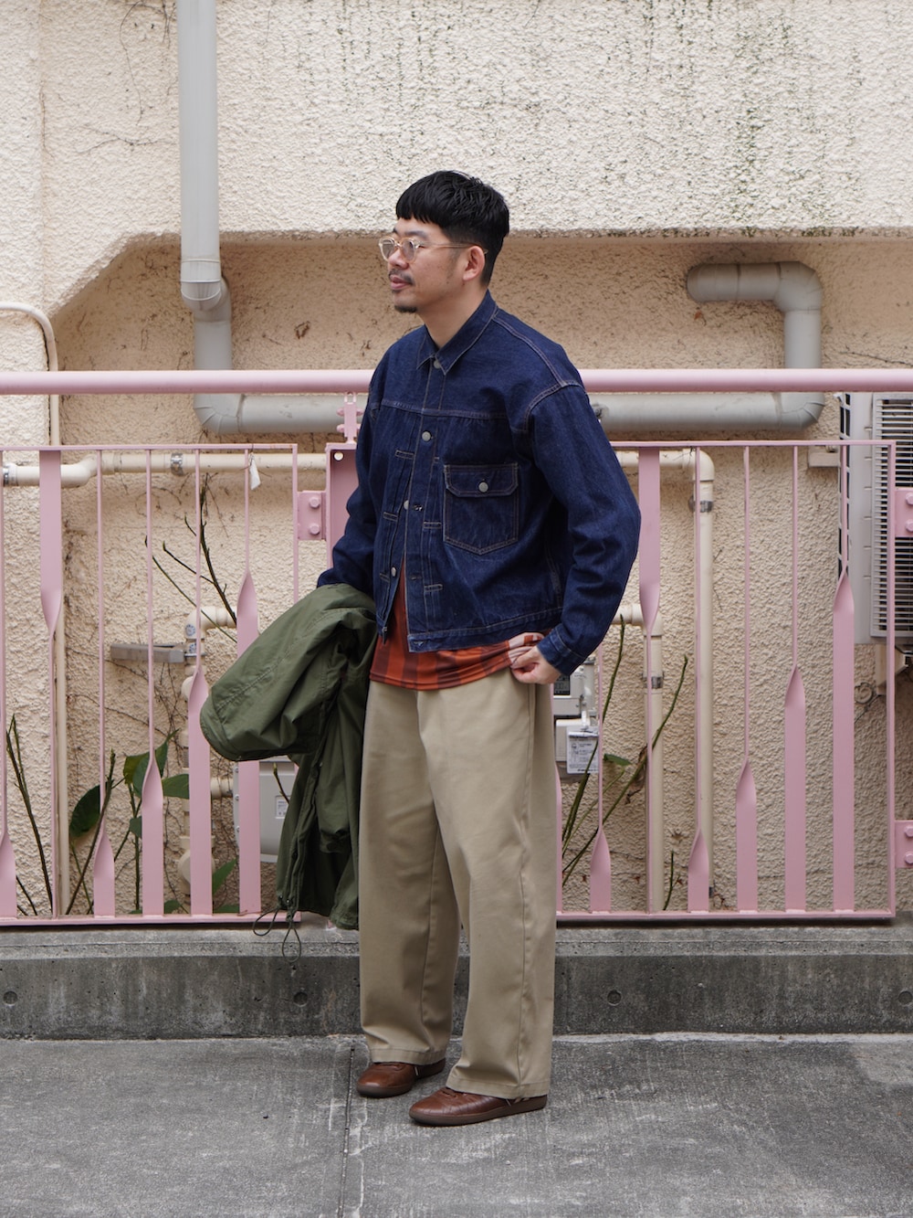 ブルー系のデニムジャケット、レッド系のトップス、グリーン系のモッズコートを着用したメンズの春コーディネートの2枚目の写真