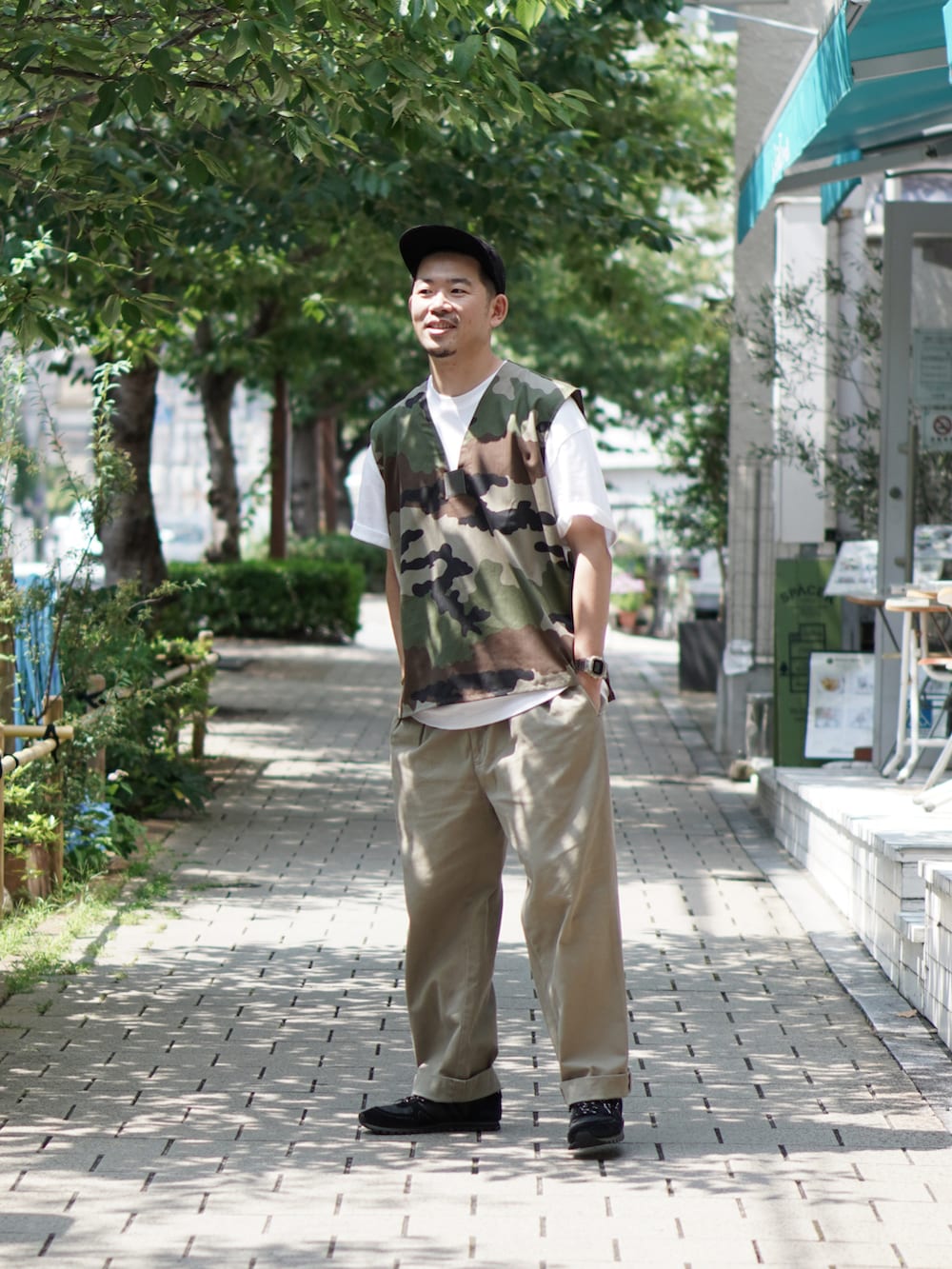 グリーン系のベスト、ホワイト系のTシャツ/カットソー、ベージュ系のチノパンツを着用したメンズの夏コーディネートの2枚目の写真