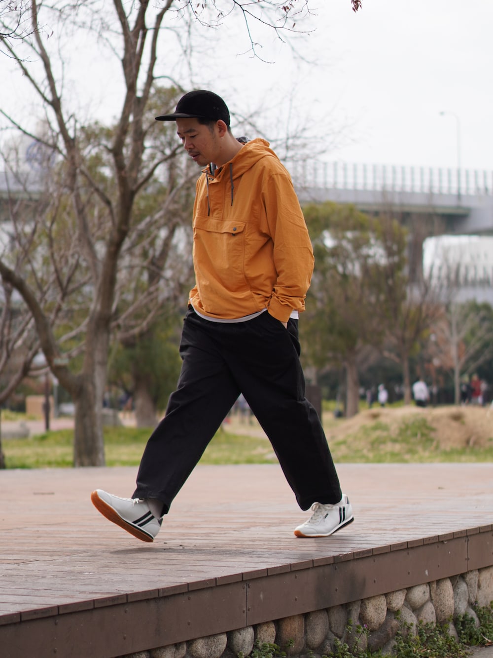 ホワイト系のTシャツ/カットソー、ブラック系のチノパンツ、オレンジ系のマウンテンパーカーを着用したメンズの春コーディネートの2枚目の写真