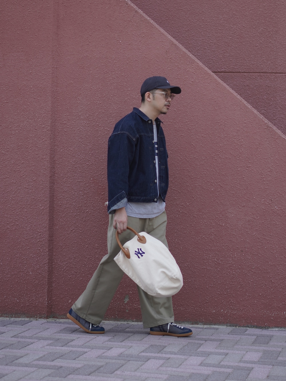 ベージュ系のチノパンツ、ホワイト系のトートバッグ、ブルー系のスニーカーを着用したメンズの春コーディネートの2枚目の写真