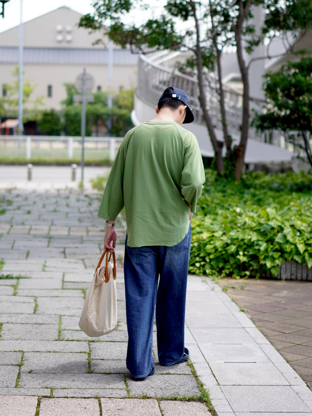 グリーン系のTシャツ/カットソー、ブルー系のデニムパンツ、ホワイト系のトートバッグを着用したメンズの夏コーディネートの2枚目の写真