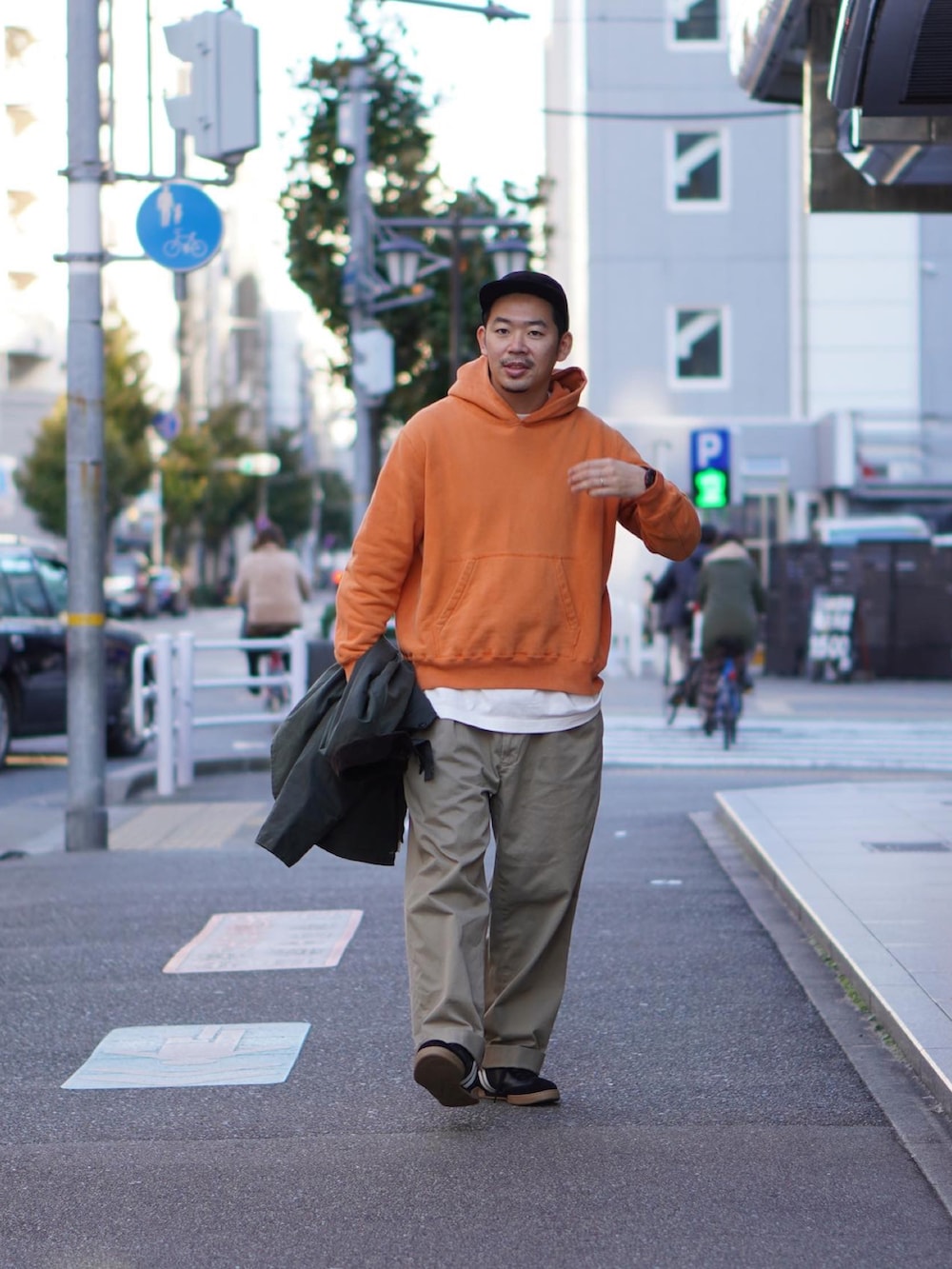 オレンジ系のパーカー、ホワイト系のTシャツ/カットソー、グリーン系のジャケット/アウターを着用したメンズの冬コーディネートの2枚目の写真