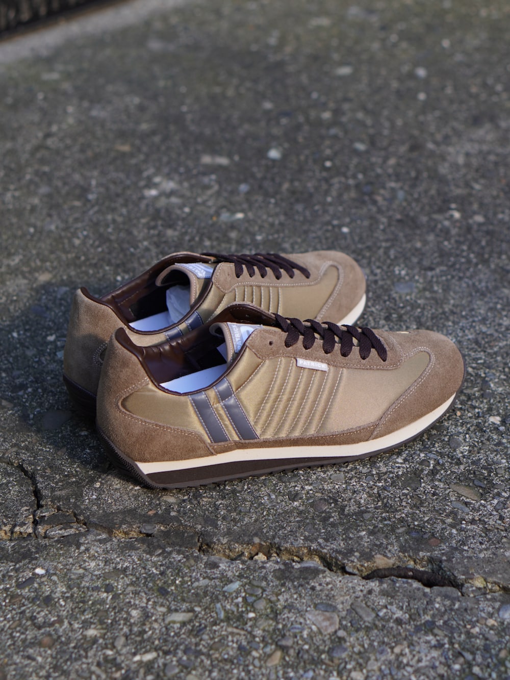 オレンジ系のナイロンジャケット、ブルー系のスウェットパンツ、ベージュ系のスニーカーを着用したメンズの秋コーディネートの2枚目の写真