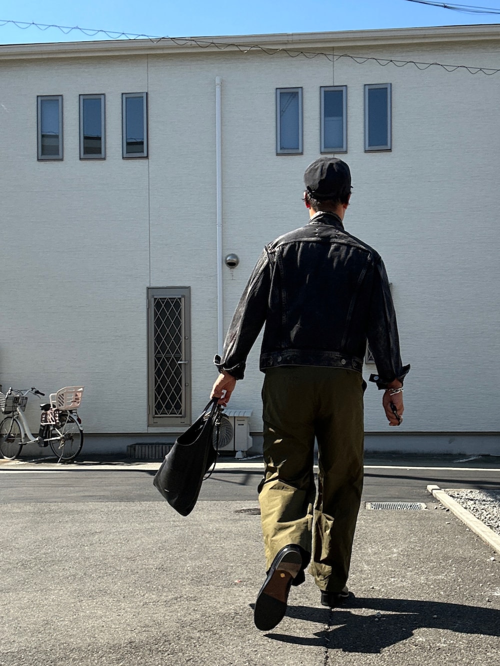 ブラック系のデニムジャケット、グリーン系のチノパンツ、ブラック系のショルダーバッグを着用したメンズの秋コーディネートの2枚目の写真