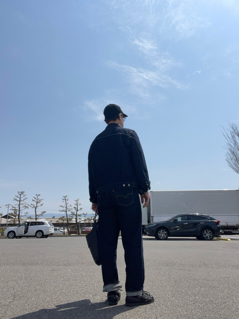 ホワイト系のTシャツ/カットソー、ブラック系のショルダーバッグ、ブルー系のデニムパンツを着用したメンズの春コーディネートの2枚目の写真