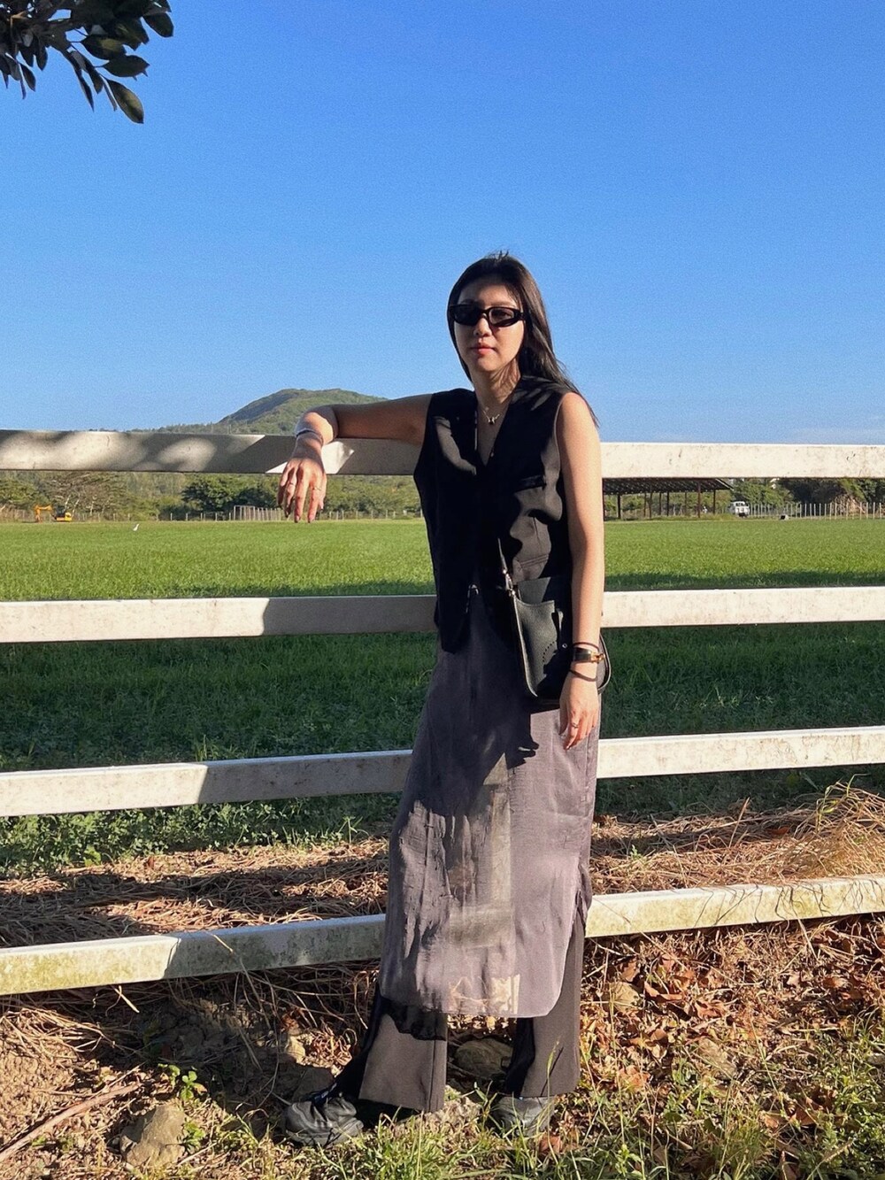 ブラック系のショルダーバッグ、ブラック系のスニーカー、グレー系のワンピースを着用したレディースの冬コーディネートの2枚目の写真