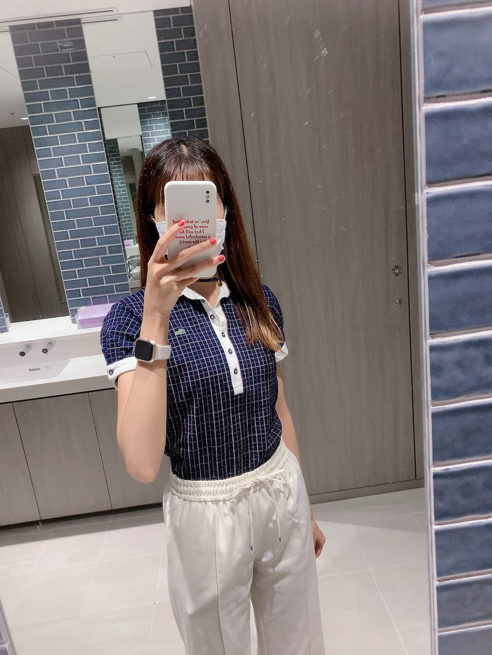 ブルー系のポロシャツ、ホワイト系のスラックスを着用したレディースの夏コーディネートの2枚目の写真