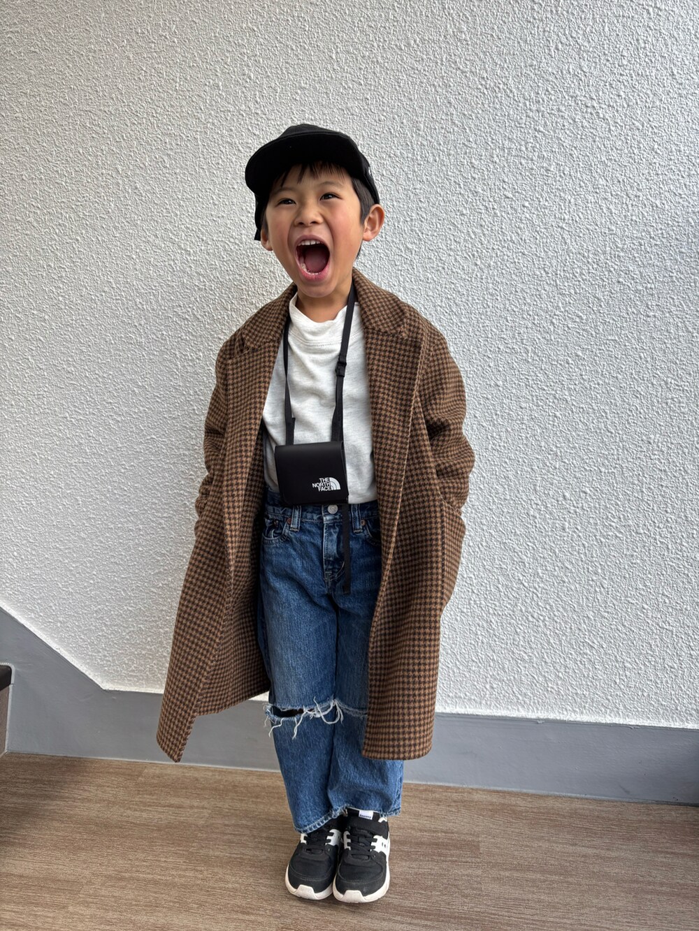 ブラウン系のチェスターコート、グレー系のスウェット、ブルー系のデニムパンツを着用したキッズの春コーディネートの2枚目の写真