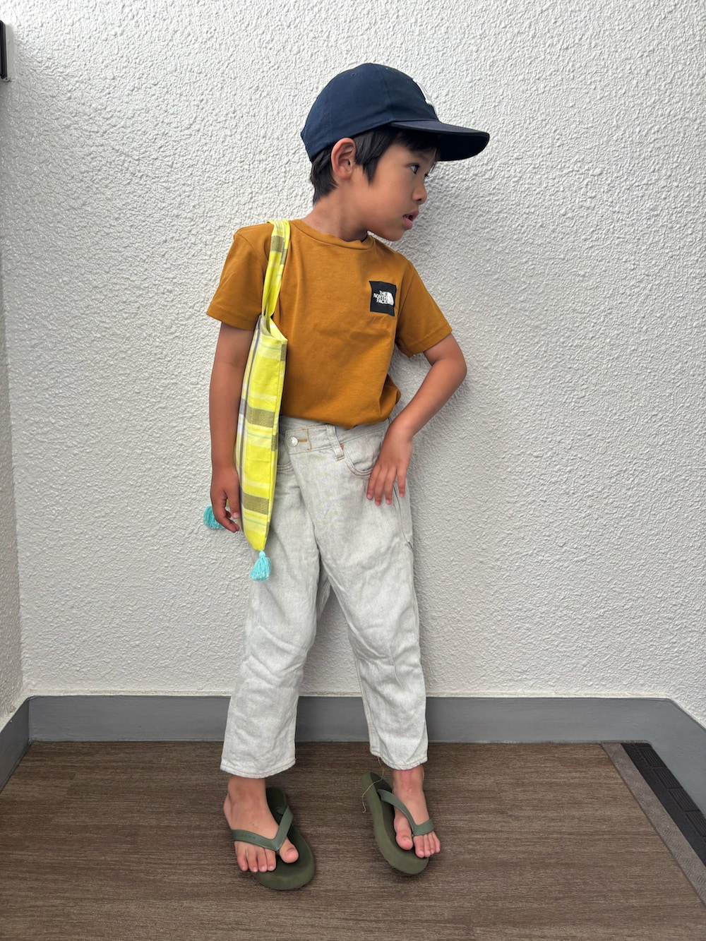 ブラウン系のTシャツ/カットソー、グレー系のデニムパンツ、イエロー系のエコバッグ/サブバッグを着用したキッズの夏コーディネートの2枚目の写真