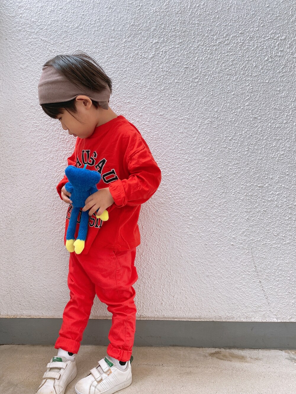 レッド系のTシャツ/カットソー、レッド系のチノパンツ、ホワイト系のスニーカーを着用したキッズの秋コーディネートの2枚目の写真