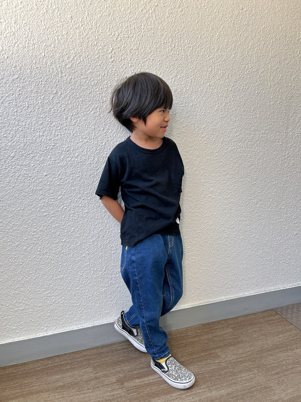 ブラック系のTシャツ/カットソー、ブルー系のデニムパンツ、ホワイト系のスリッポンを着用したキッズの秋コーディネートの2枚目の写真
