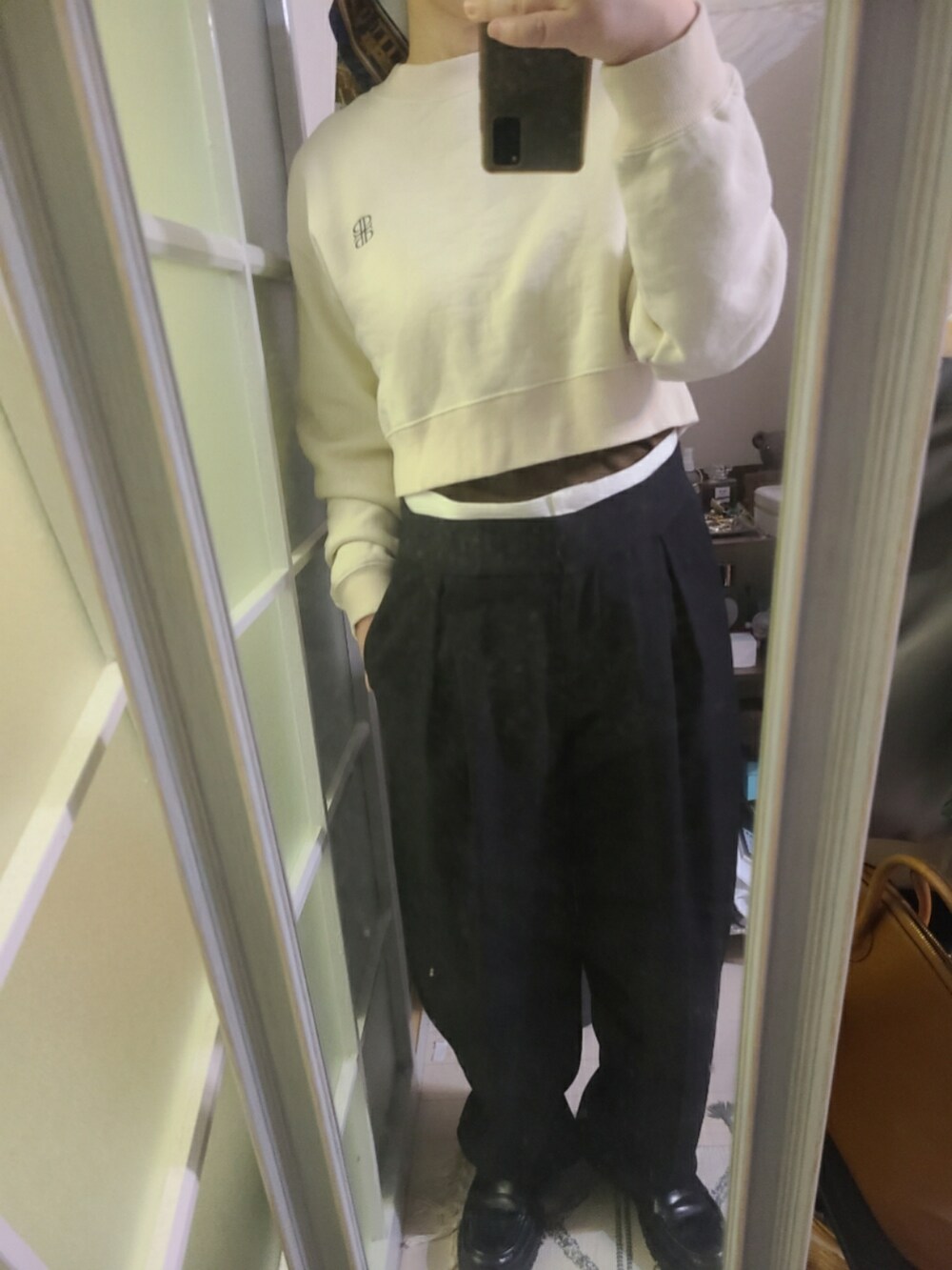 ベージュ系のスウェット、ブラック系のスラックス、ブラック系のローファーを着用したレディースの春コーディネートの2枚目の写真