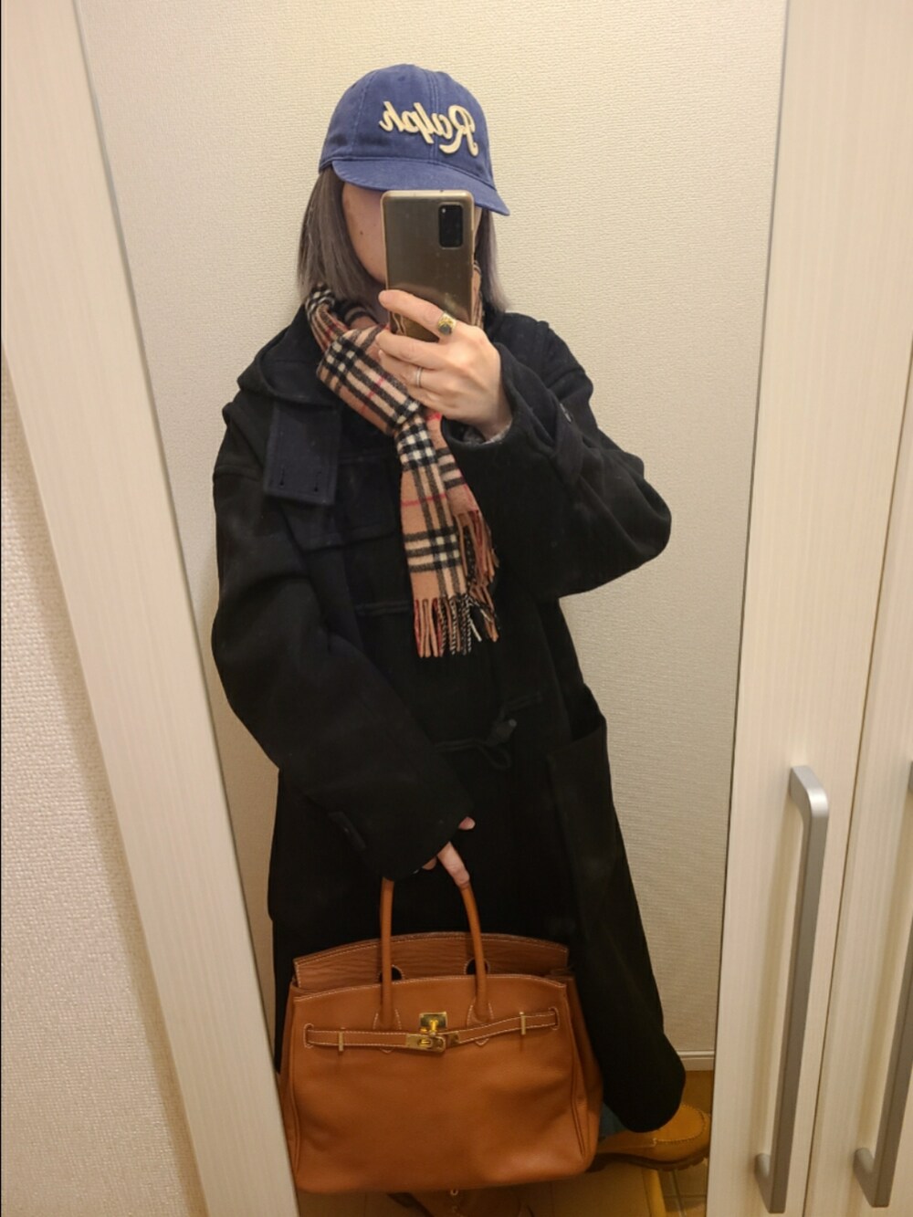 ブラウン系のトートバッグ、ブラウン系のブーツ、ブルー系のデニムパンツを着用したレディースの冬コーディネートの3枚目の写真