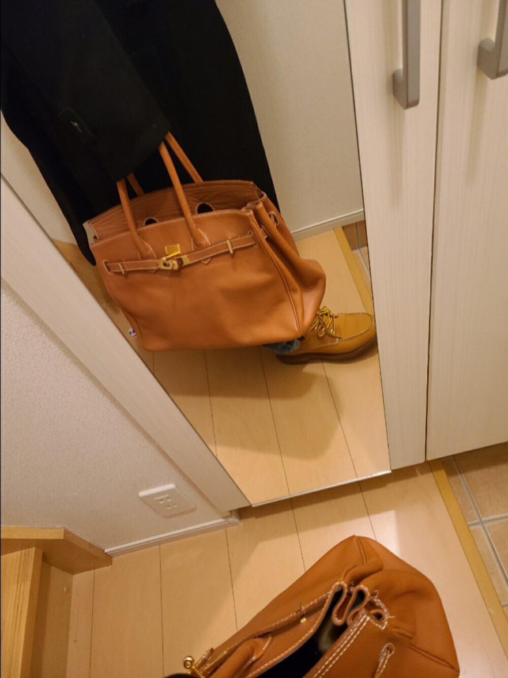 ブラウン系のトートバッグ、ブラウン系のブーツ、ブルー系のデニムパンツを着用したレディースの冬コーディネートの2枚目の写真