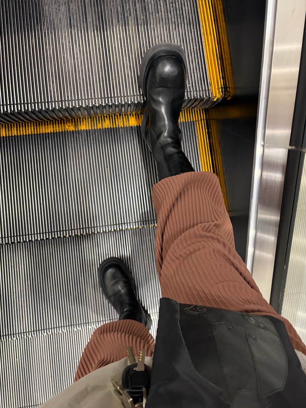 グレー系のダウンジャケット/コート、ブラック系のショルダーバッグ、ブラウン系のスラックスを着用したメンズの冬コーディネートの2枚目の写真