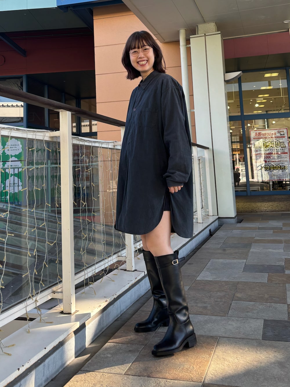 ブラック系のブーツ、ゴールド系のメガネを着用したレディースの秋コーディネートの3枚目の写真